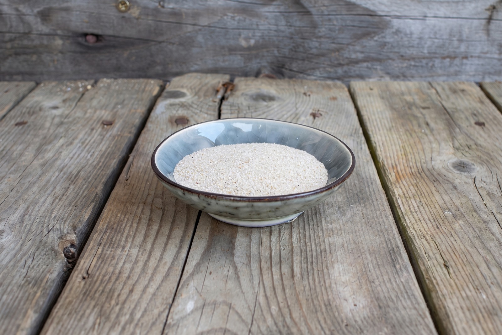 R&auml;ucherschale mit Sand steht zum R&auml;uchern bereit auf einem Holztisch
