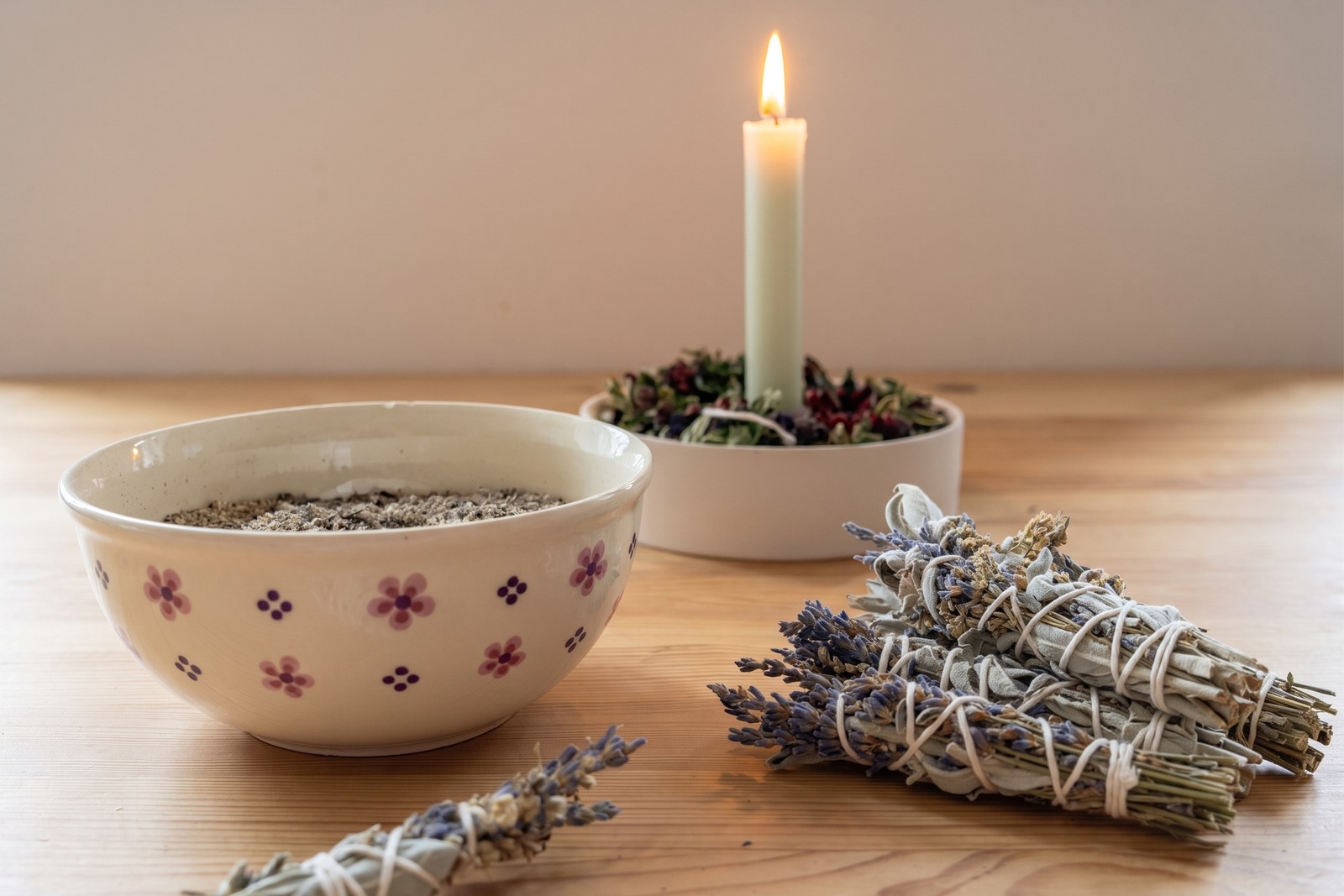 Räucherbündel aus Salbei und Lavendel neben Schale und brennender Kerze